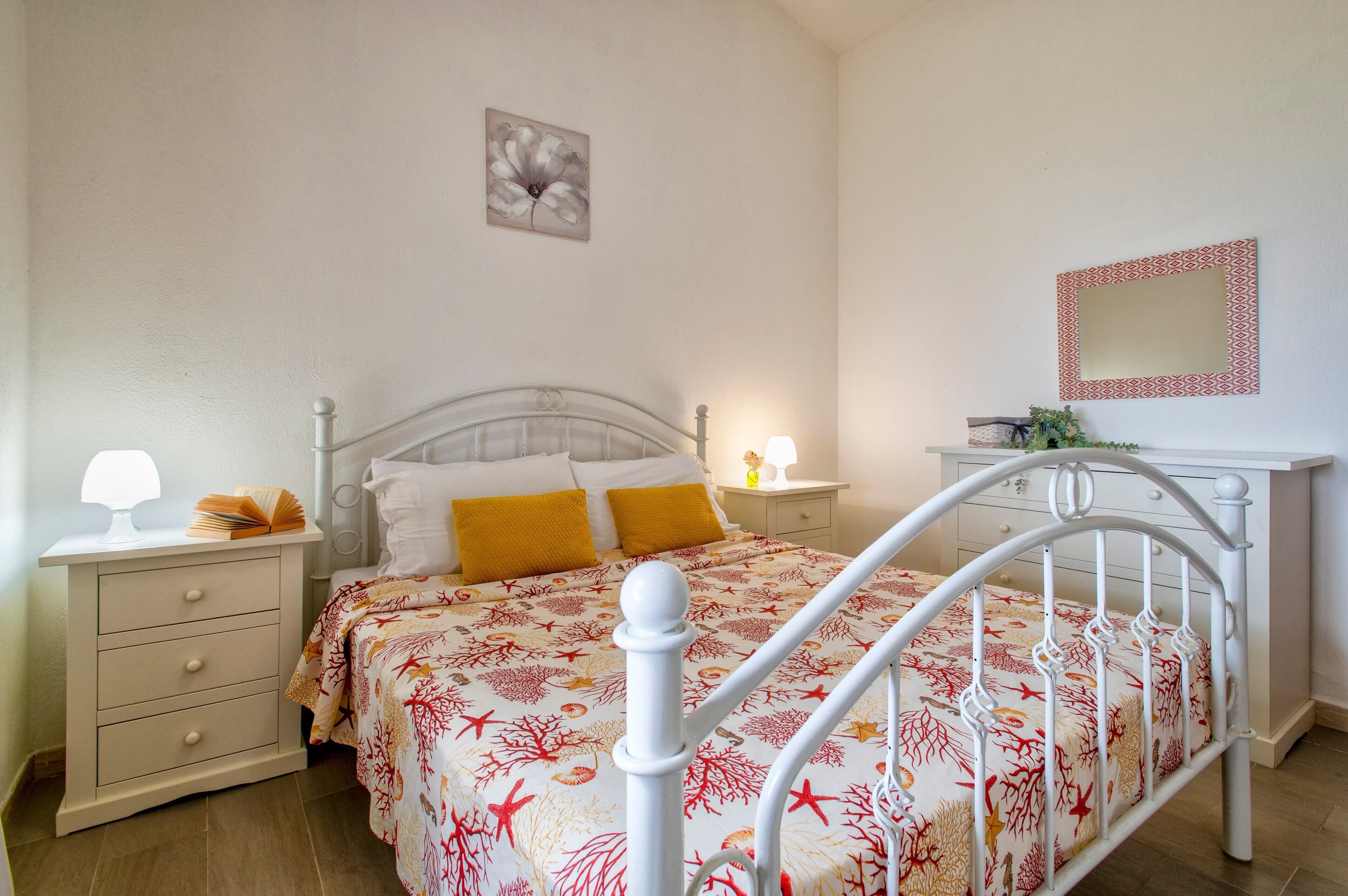 Ein Schlafzimmer mit Bett, Nachttisch, Schminktisch und Spiegel.