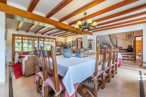 A dining area with wooden chairs, a table with a white tablecloth, and a chandelier.