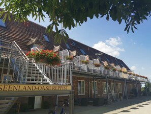 Edifici amb un cartell que diu "SEENLAND-OASE REPPIST" i una escala que condueix a un balcó amb jardineres florals.