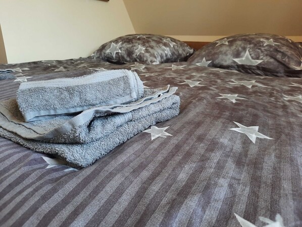 A bed with a star-patterned bedspread and a folded towel on it.