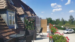 A patio with outdoor furniture, a wooden fence, and a car parked in the background. - Room 1 - Lakeland oasis Reppist (Senftenberg)