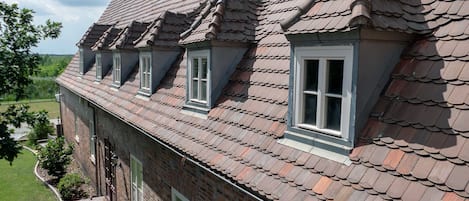 Um edifício de dois andares de tijolo, com telhado inclinado e janelas salientes.