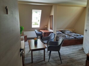 Une petite chambre à coucher, de taille réduite, comprenant un lit simple, un bureau et deux chaises.