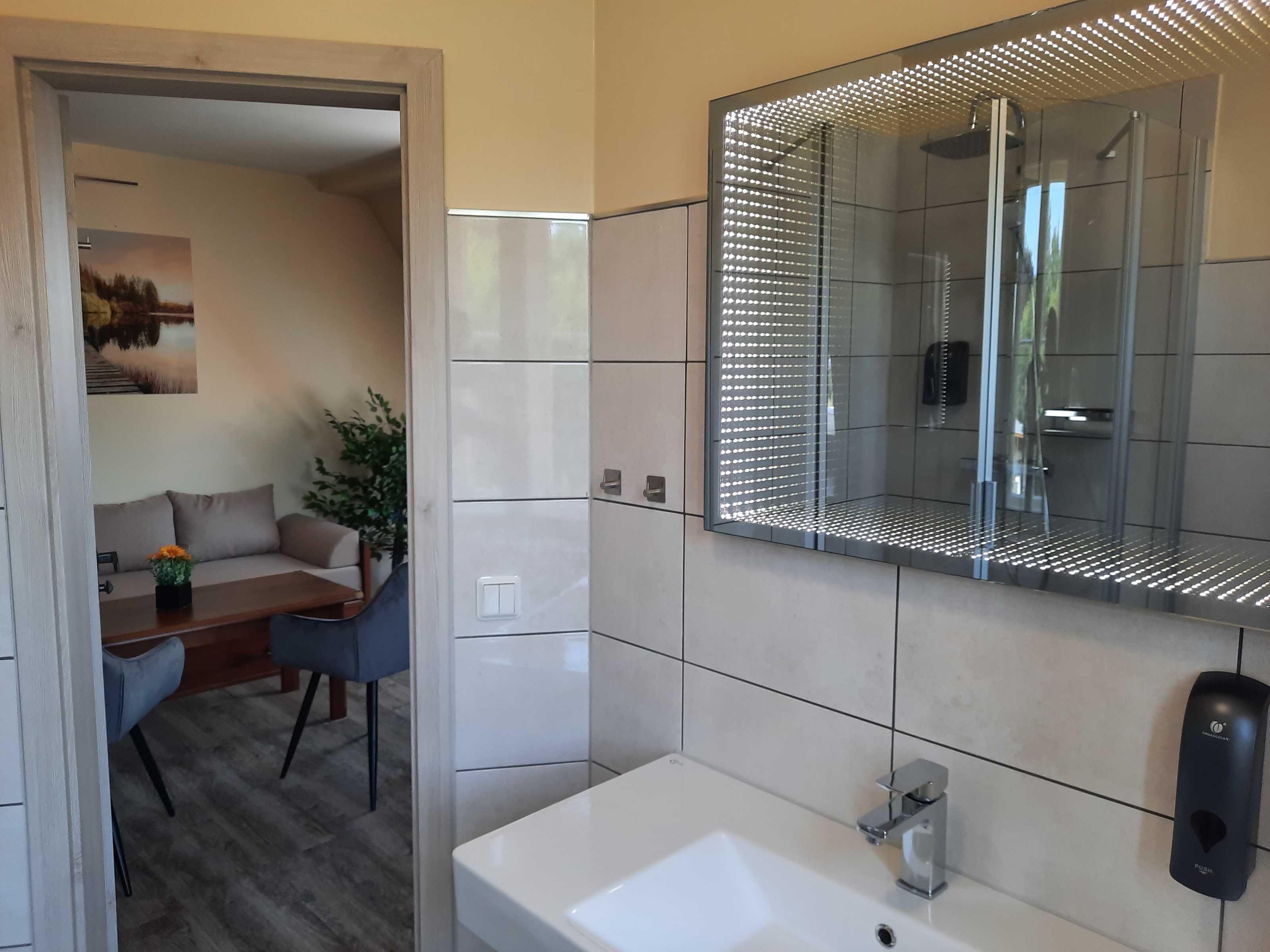 A modern bathroom with a large mirror, a white sink, and a glass shower enclosure.