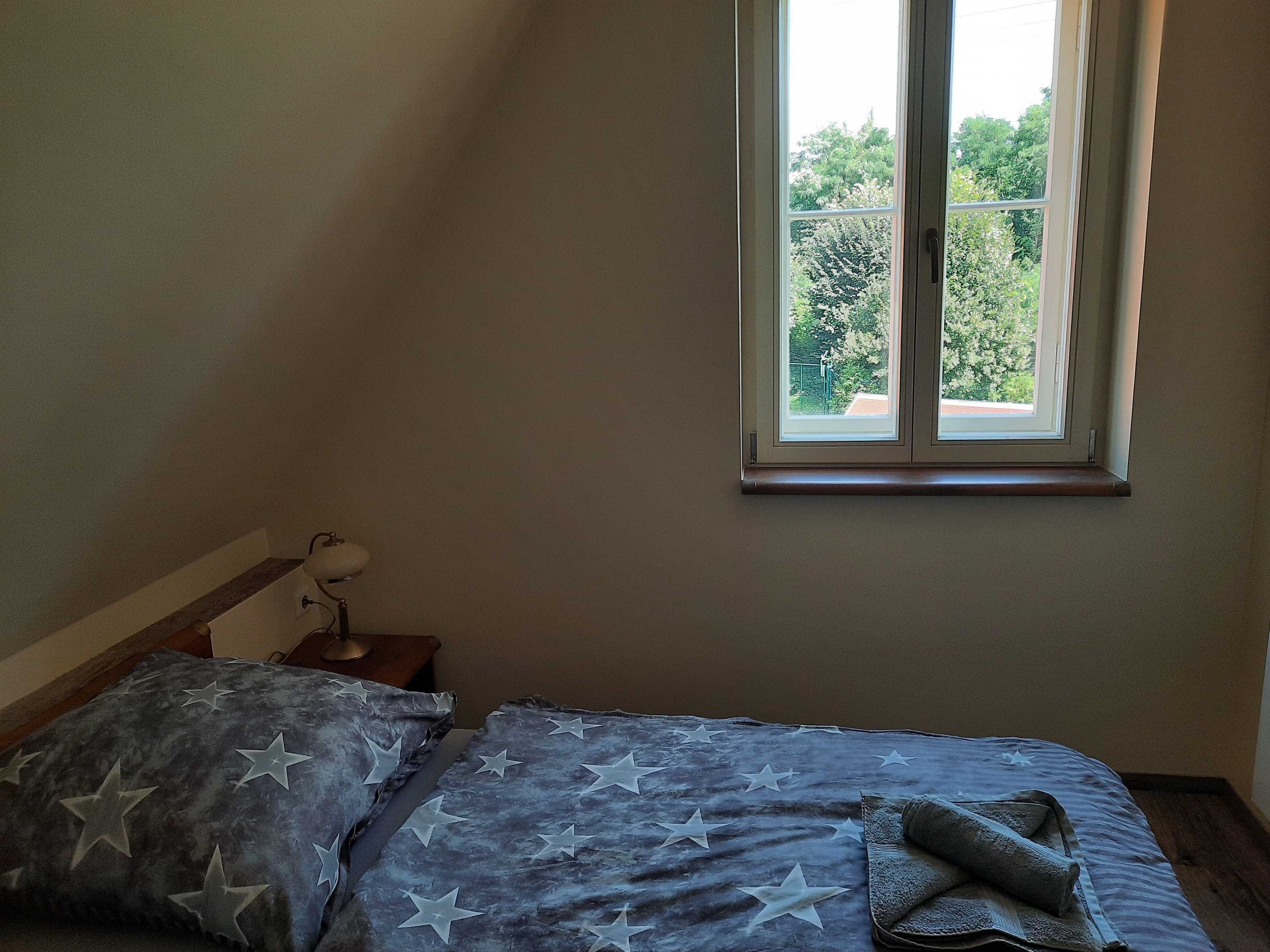Een slaapkamer met een bed, een raam en een nachtkastje.