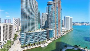 A high-rise hotel with multiple floors, a waterfront promenade, and a marina with boats. - Brickell Open-Concept Suite for Groups (Miami)
