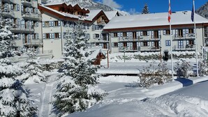 Un hotel cubierto de nieve con varios balcones y un paisaje montañoso de fondo.