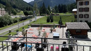 Una terraza con asientos al aire libre, vistas a la montaña y un edificio con tejado inclinado.