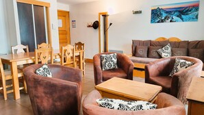 Una sala de estar acogedora con un sofá marrón, una mesa de centro de madera y una zona de comedor con una mesa y sillas de madera.