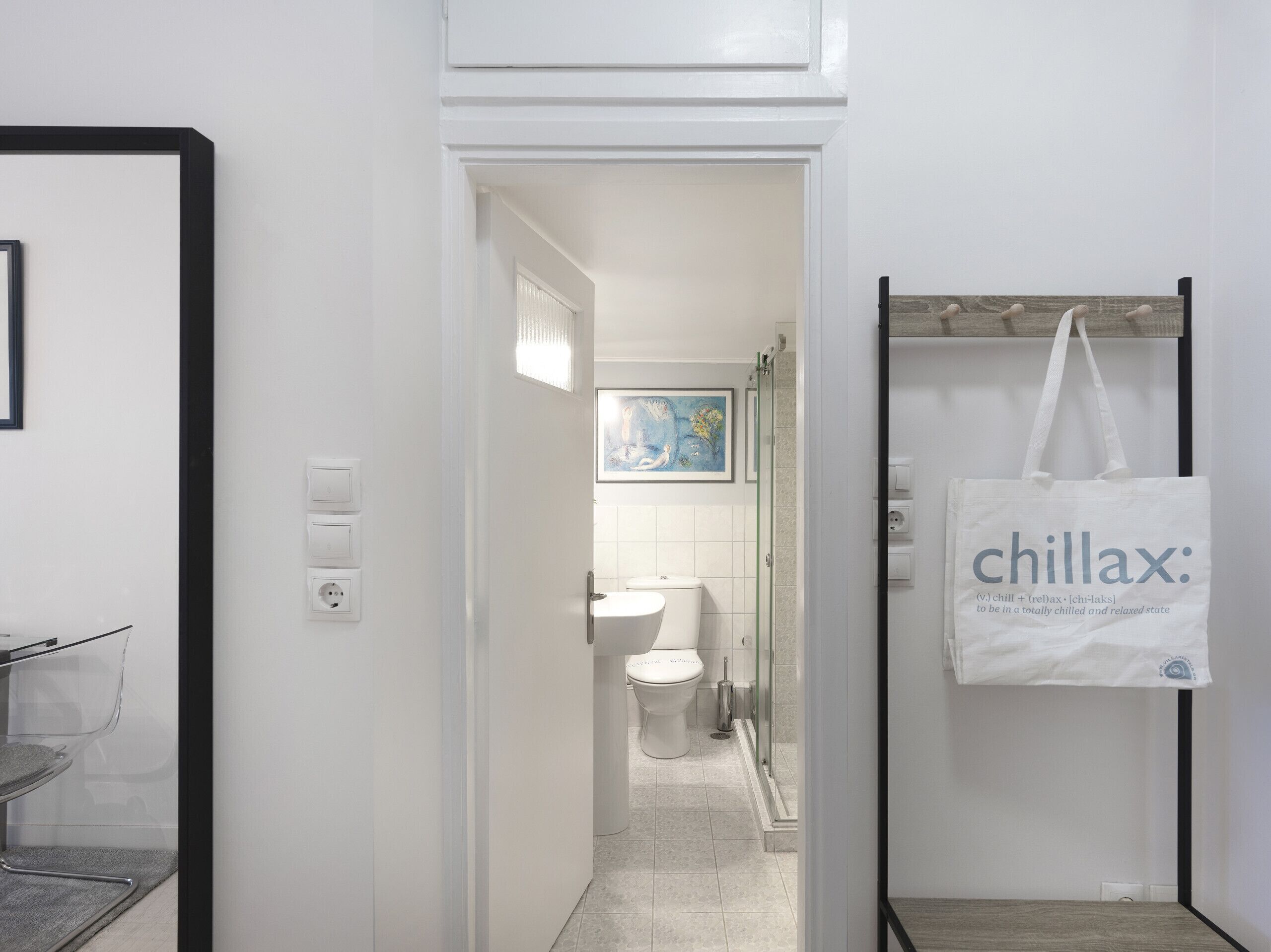 A bathroom with a toilet, shower, and a towel rack with a bag.
