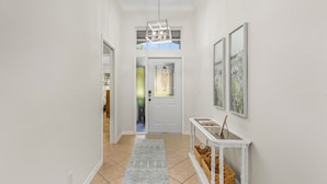 A hallway with a white door, a white console table with baskets, and a patterned rug. - 14090 Oasis w/ Pool, Near Beach (Fort Myers)