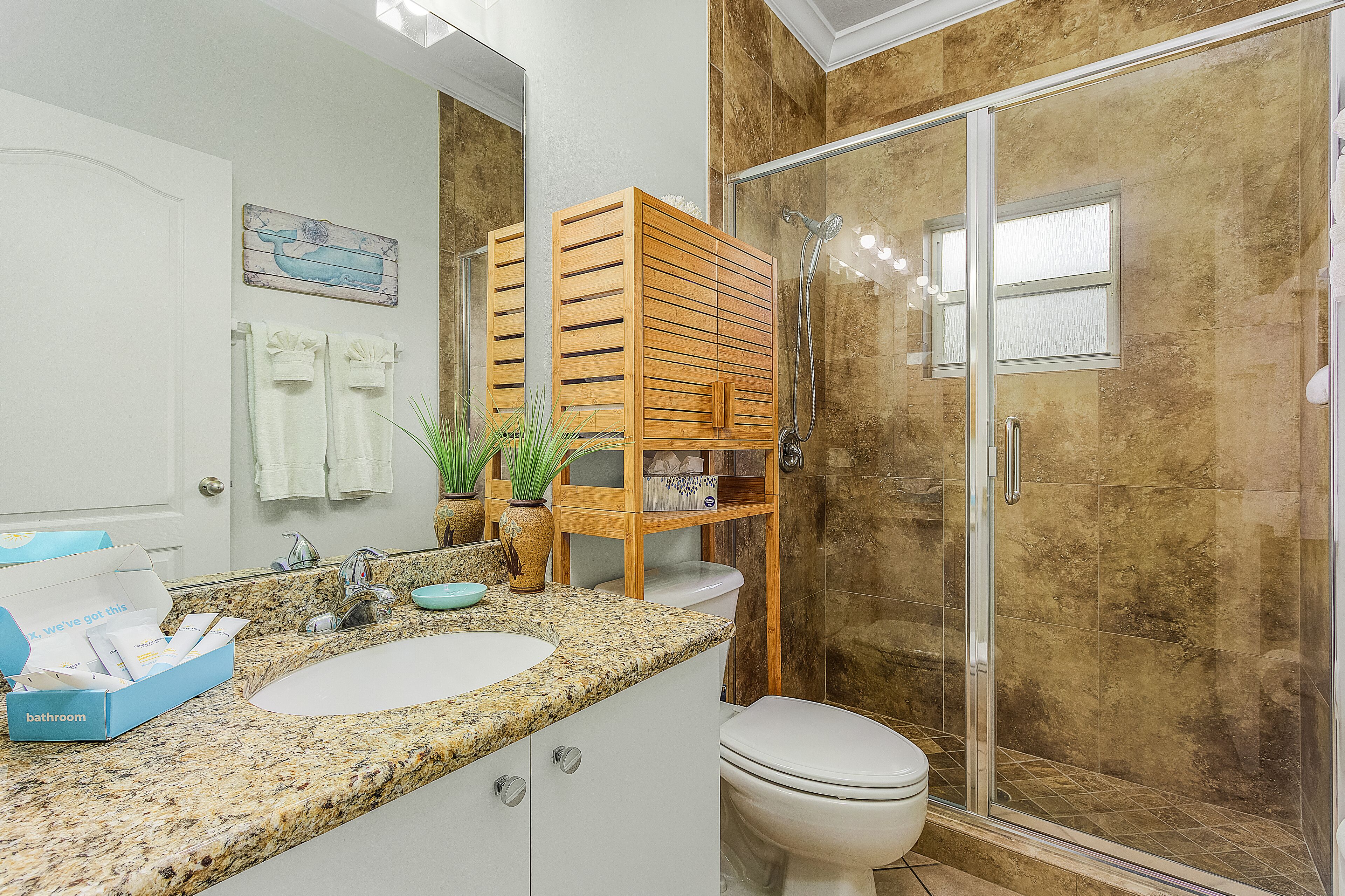 Un baño con dos lavamanos, inodoro, ducha y una estantería de madera.