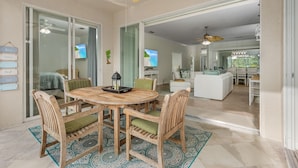 A spacious living area with a wooden dining table, green cushioned chairs, and a ceiling fan. - 14090 Oasis w/ Pool, Near Beach (Fort Myers)