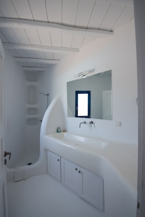 A modern bathroom with a freestanding bathtub, a large mirror, and a white vanity. - Villa Victoria (Mykonos)
