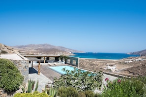 A pool area with a view of the sea and mountains. - Villa Victoria (Mykonos)