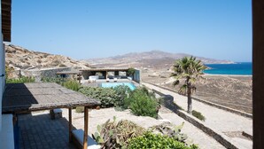 Una villa con piscina, zona de estar exterior y vistas al mar y a las montañas.