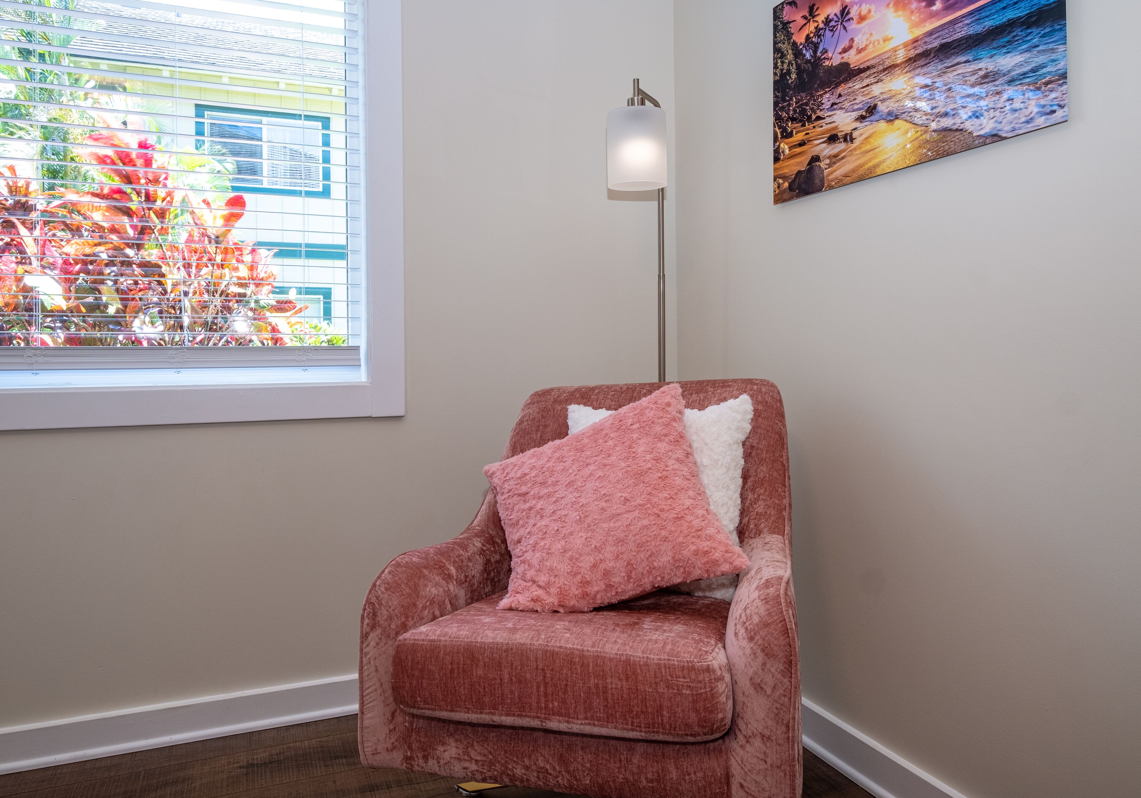 A room with a window, a floor lamp, and a painting on the wall.