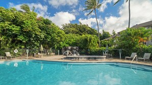 A swimming pool with lounge chairs and a waterfall feature.
