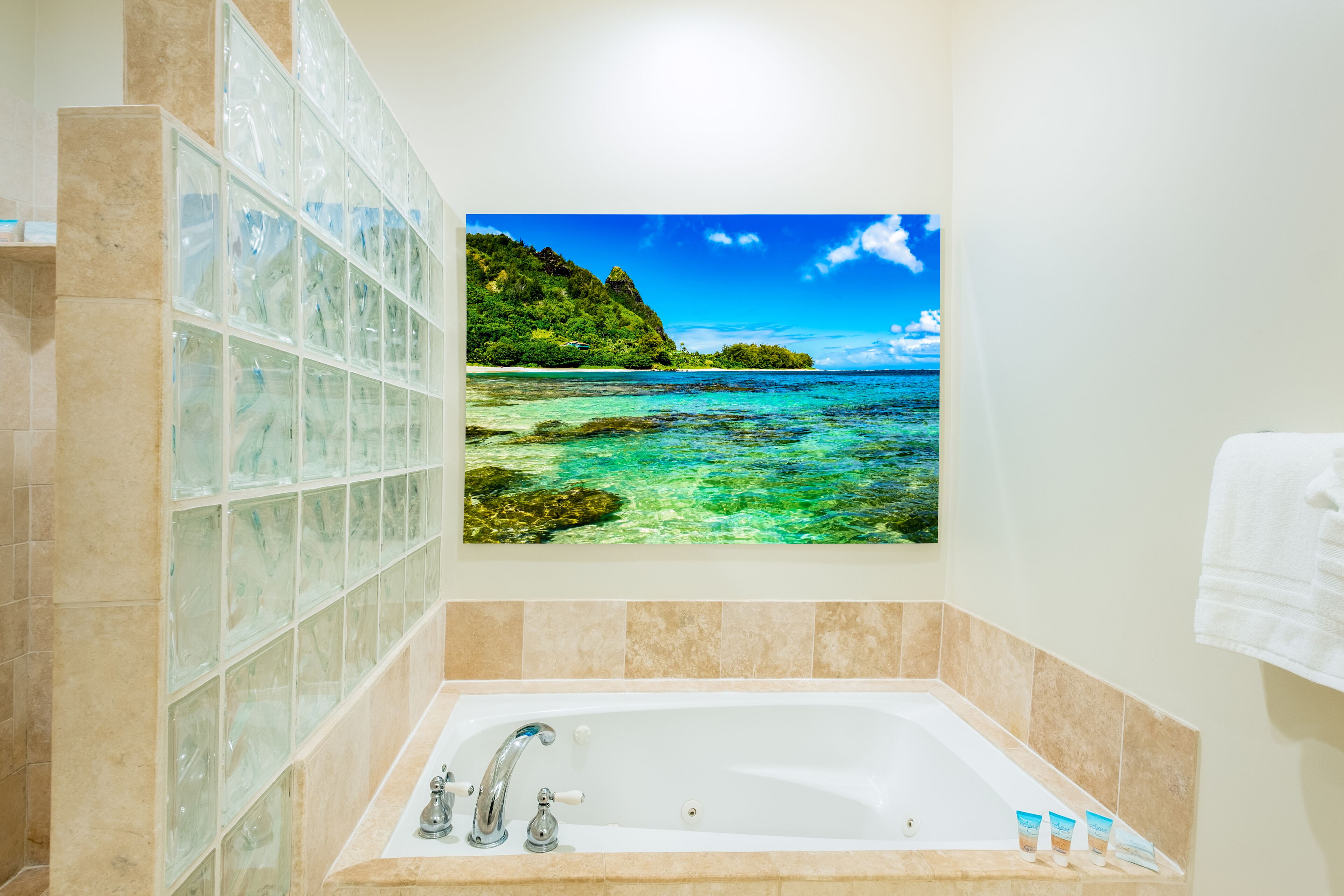 A bathroom with a large bathtub, a glass shower enclosure, and a scenic ocean view.