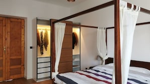 A four-poster bed with a striped bedspread, a wooden wardrobe, and a mirror cabinet. - Designer Apartment 110m² w/ King Beds, Balcony, Smart TV + Equipped Kitchen (Kraków)