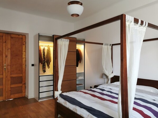 Ein Himmelbett mit gestreifter Bettdecke, ein Holzschrank und ein Schminkspiegel.