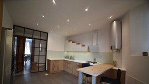 A modern kitchen with a wooden table and chairs, a built-in oven, and a large window. - Designer Apartment 110m² w/ King Beds, Balcony, Smart TV + Equipped Kitchen (Kraków)