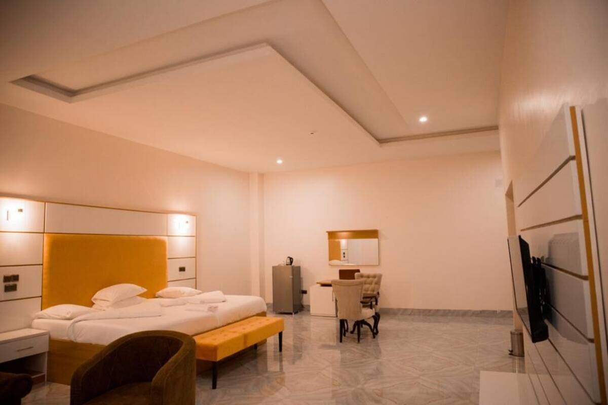 Quarto de hotel moderno com uma cama grande, uma escrivaninha, uma cadeira e uma televisão.