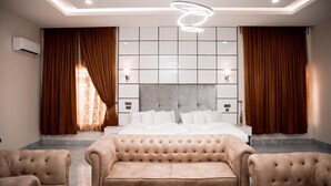 Una habitación de hotel moderna con una cama grande, un sofá capitonado y una mesa de centro.