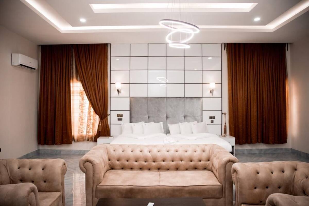 Quarto de hotel moderno com uma cama grande, um sofá estofado e uma mesa de centro.