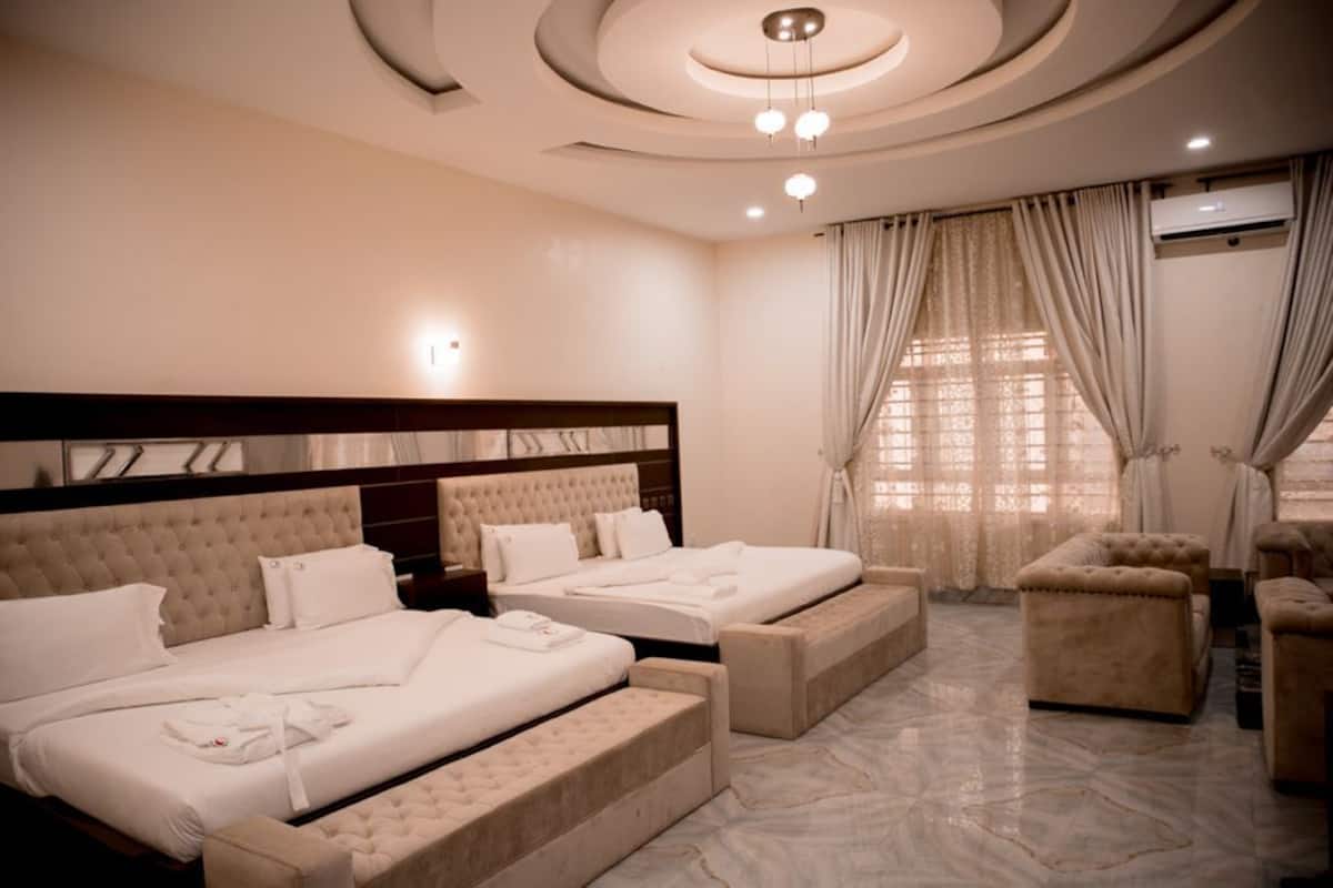 Quarto de hotel com duas camas, um sofá e uma pequena mesa.