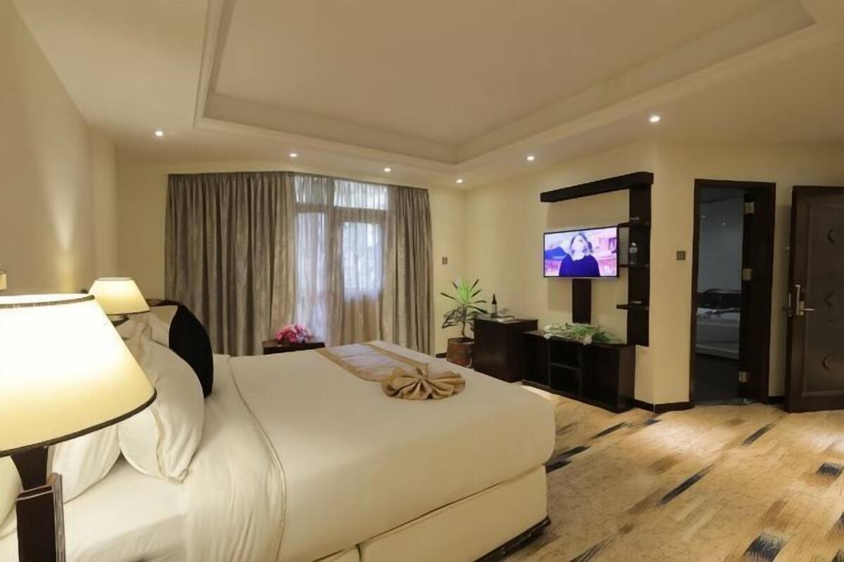 Una habitación de hotel con cama, televisión, escritorio y puerta.