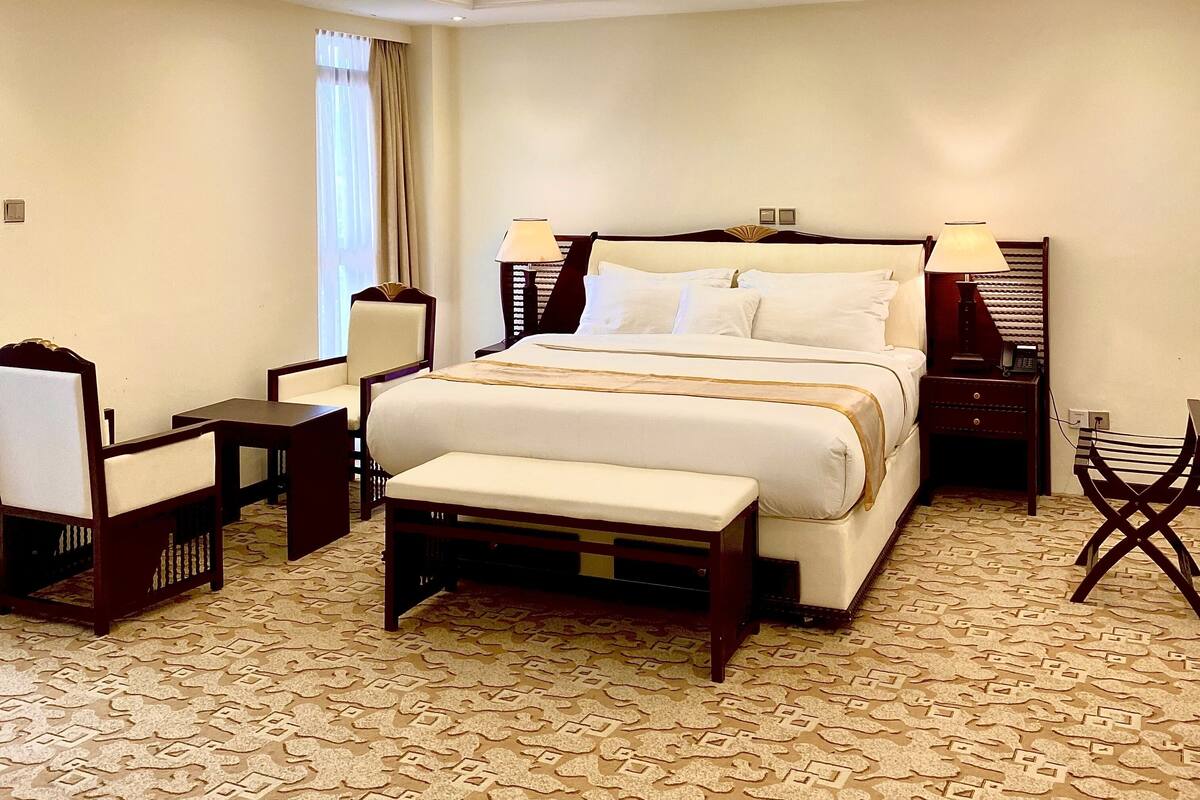 Una habitación de hotel con una cama grande, mesitas de noche, una silla y un escritorio.
