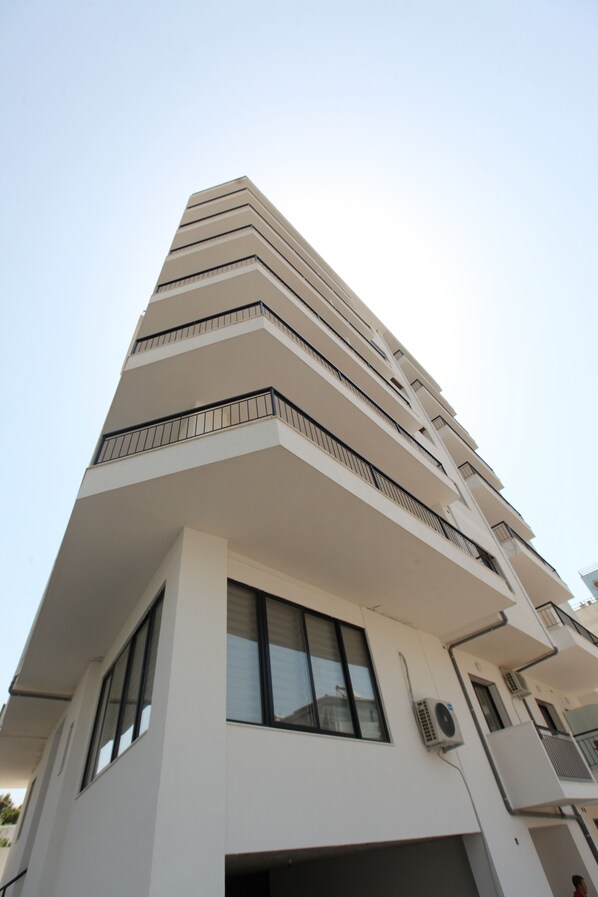A tall, modern building with a white facade, multiple balconies, and large windows. - Joanna Suites (Sarandë)
