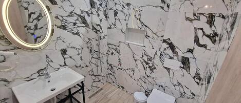 Ein Badezimmer mit Marmorwand, Waschbecken, Toilette und Dusche.
