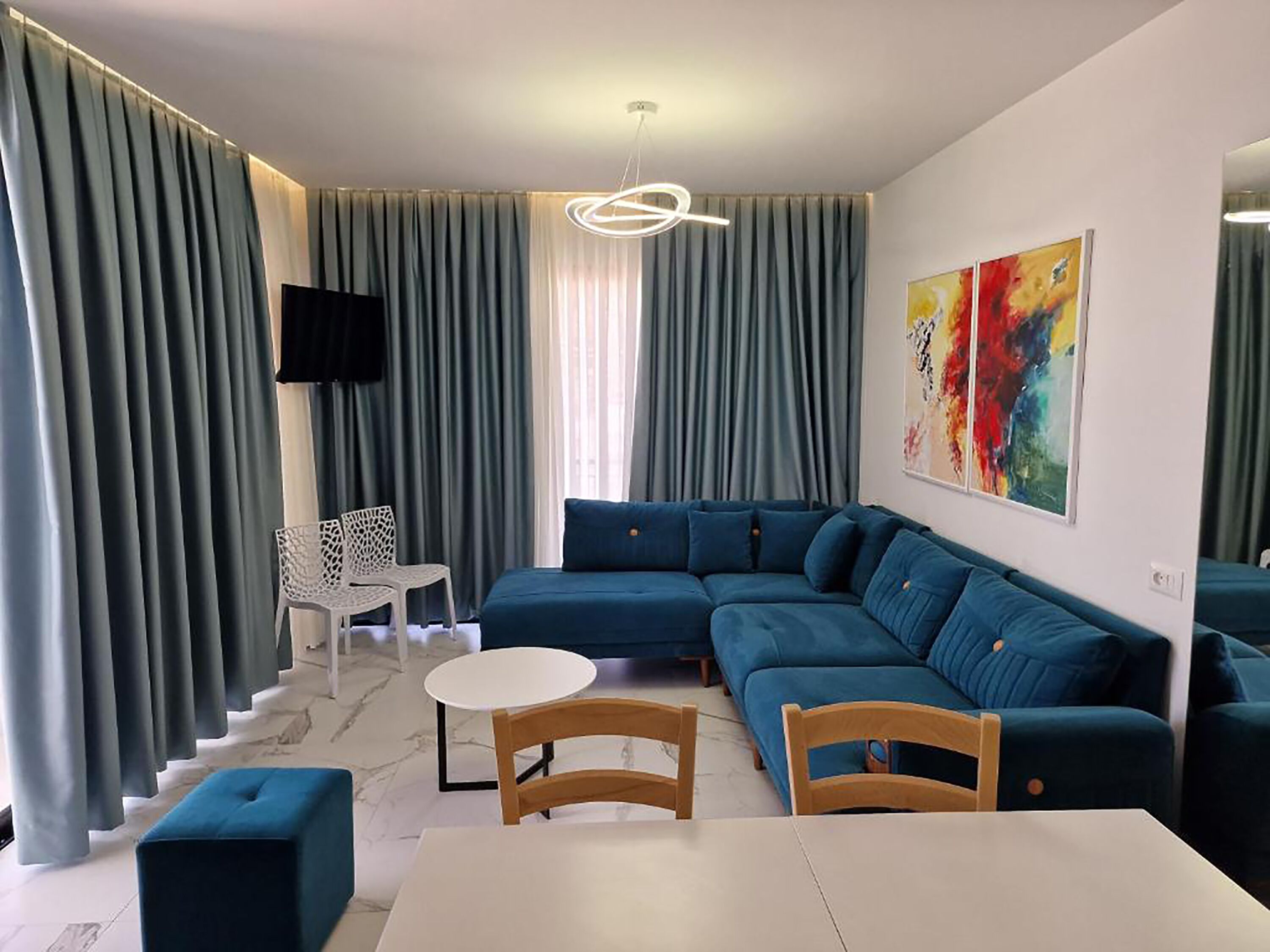 A modern living room with a sectional sofa, a white coffee table, and a TV mounted on the wall.