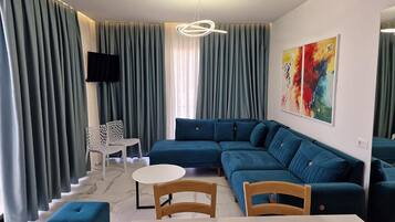 A modern living room with a sectional sofa, a white coffee table, and a TV mounted on the wall.