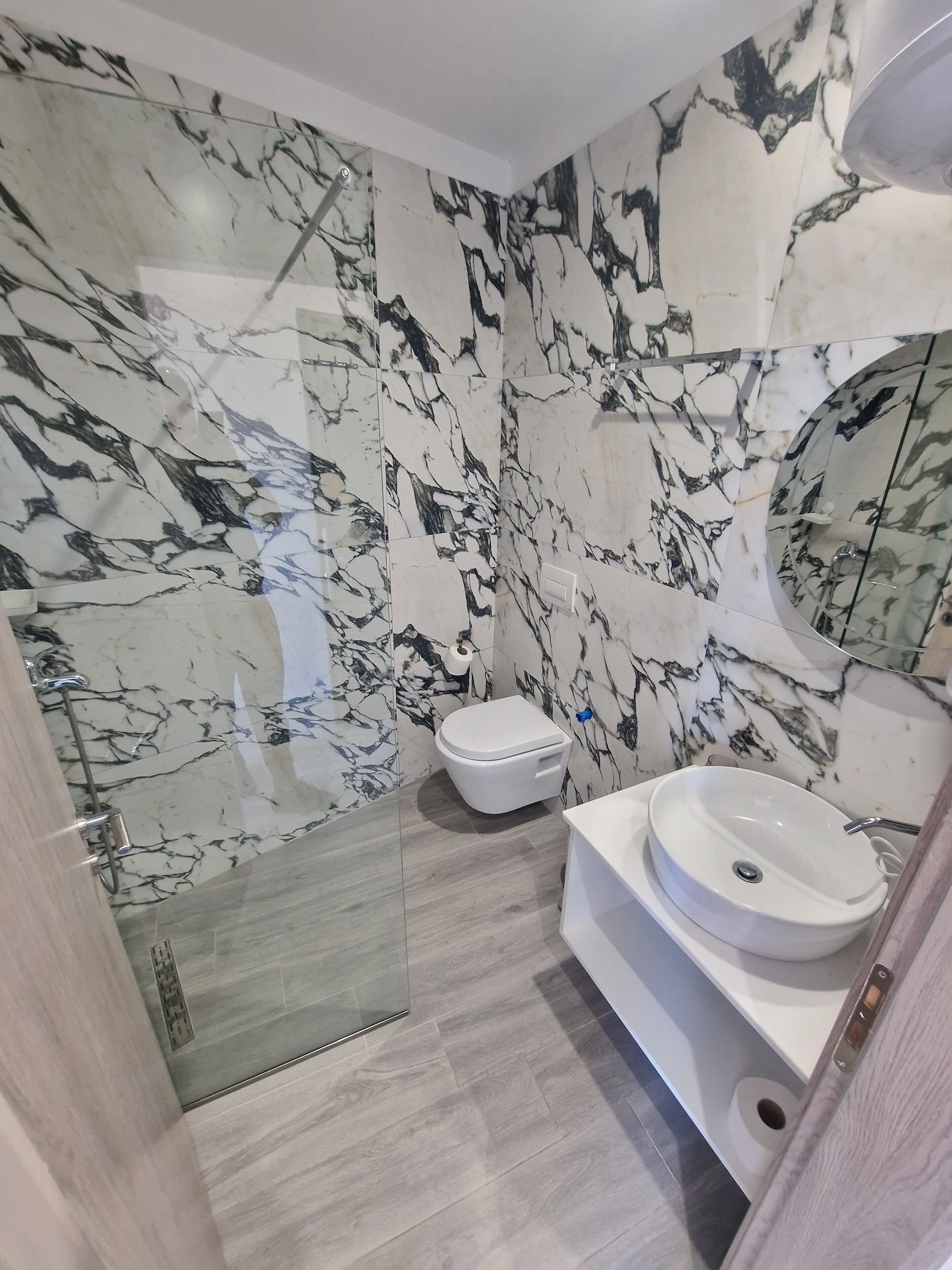 A bathroom with marble walls, a toilet, and a sink.
