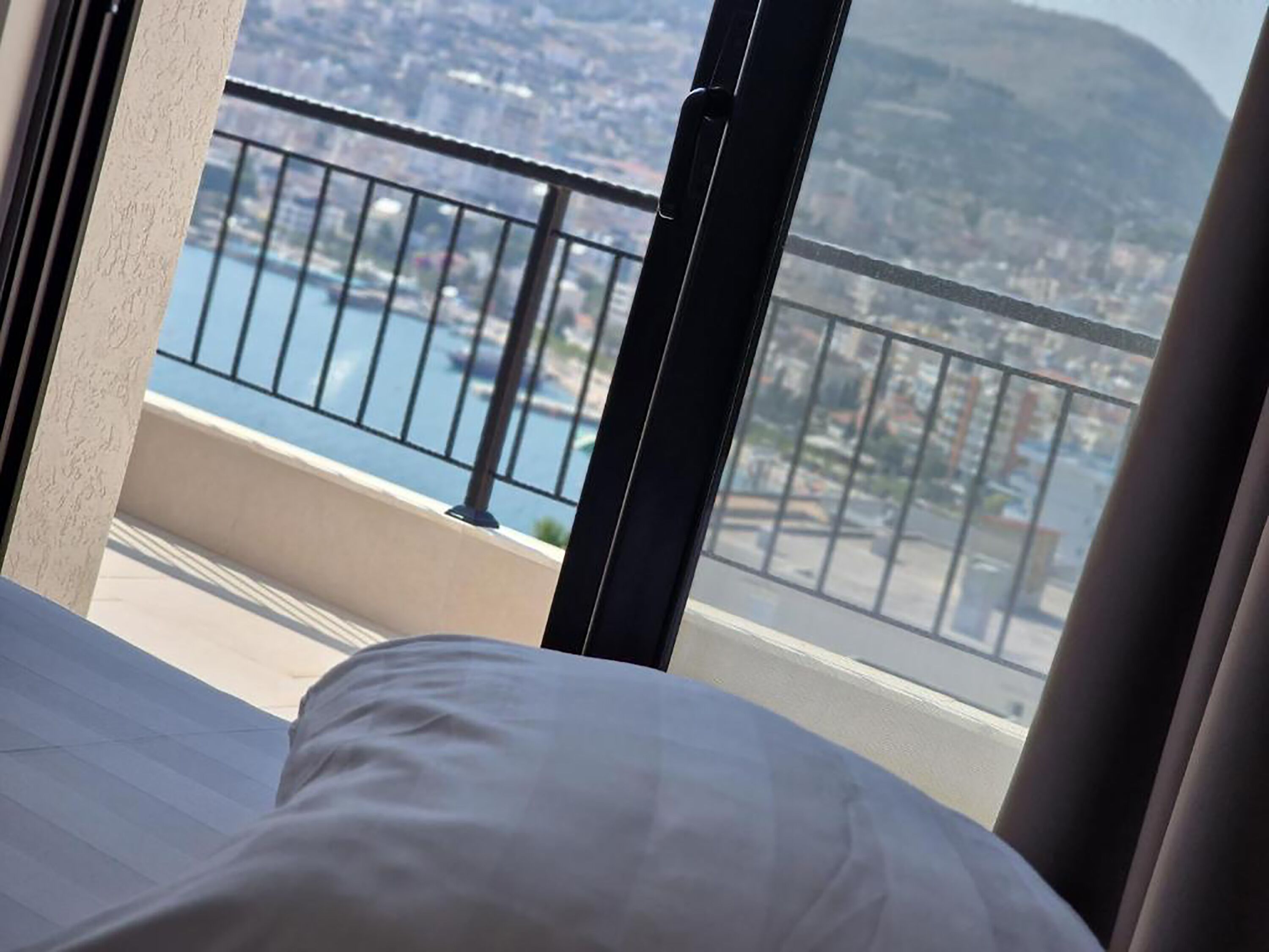 Habitación de hotel con balcón y vistas a la ciudad y al agua.