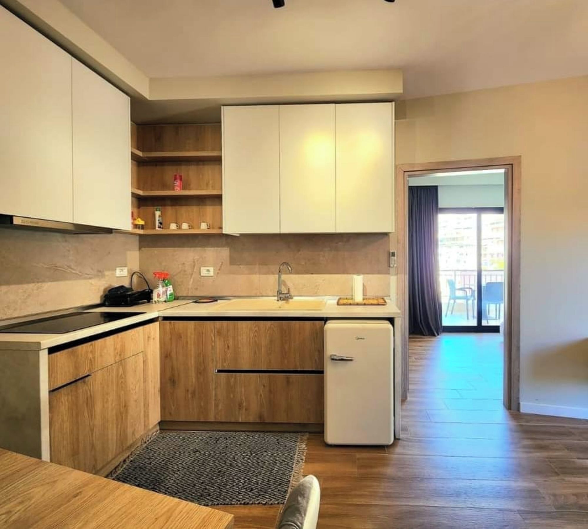 A compact kitchen with wooden cabinets, a built-in sink, and a small refrigerator.