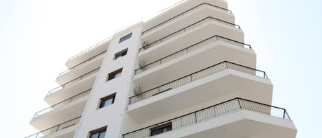 A multi-story building with balconies and large windows.