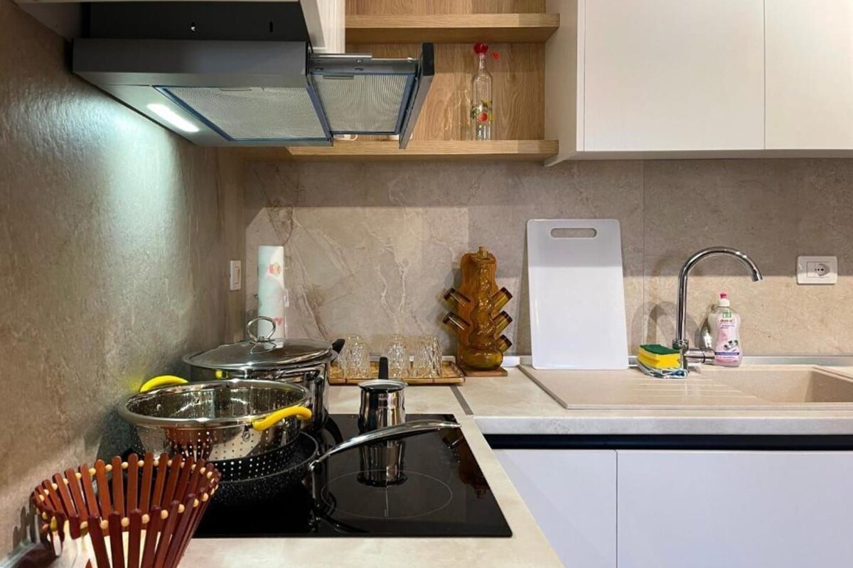 A modern kitchen with a stove, sink, and wooden cabinets.