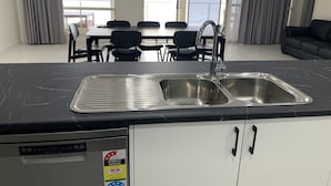 A modern kitchen with a double sink, a dining area with a table and chairs, and a view of the sea through large windows. - Beachside & Jetty View Apartment 1 (Admiral Apartment) (Streaky Bay)