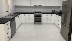 A modern kitchen with white cabinets, a stainless steel stove, and a refrigerator.
