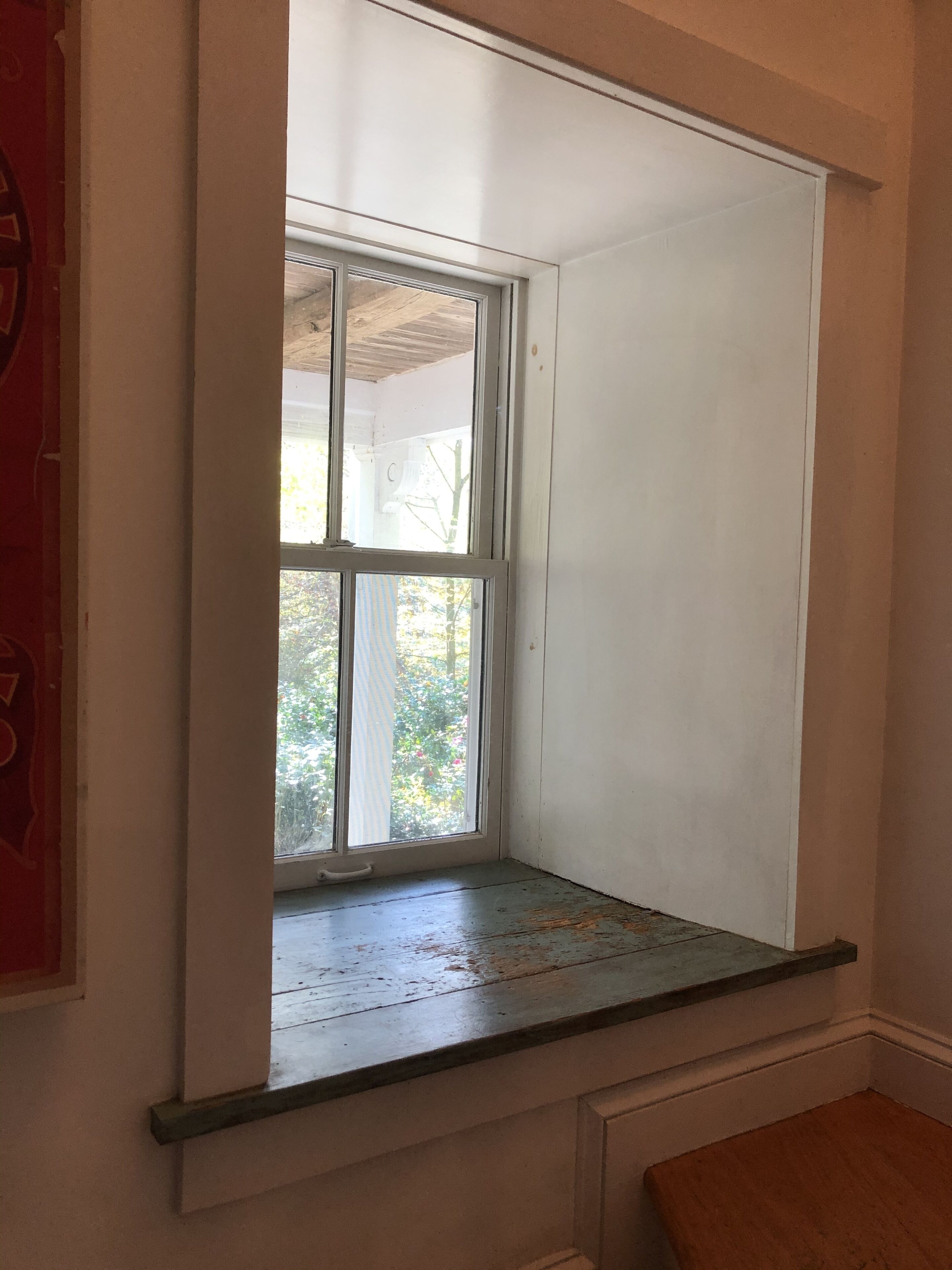 A room with a window overlooking a garden.