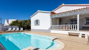 A swimming pool with a white house in the background.