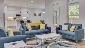A modern living room with two sofas, a coffee table, and a kitchen in the background. - Modern and Comfortable Home Close to Downtown (Dallas)