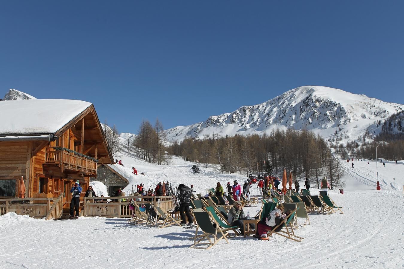 A wooden lodge with a ski slope in the background.