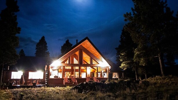 A lodge with a prominent wooden structure, large windows, and a well-lit exterior. - TrailsEndRanch ⛰Views, HotTub, Horseback riding on 1000's ac (Angel Fire)