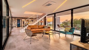 A modern living room with a sofa, chairs, a coffee table, and a TV.
