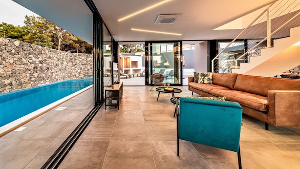A modern living room with a pool, stone wall, and a staircase.